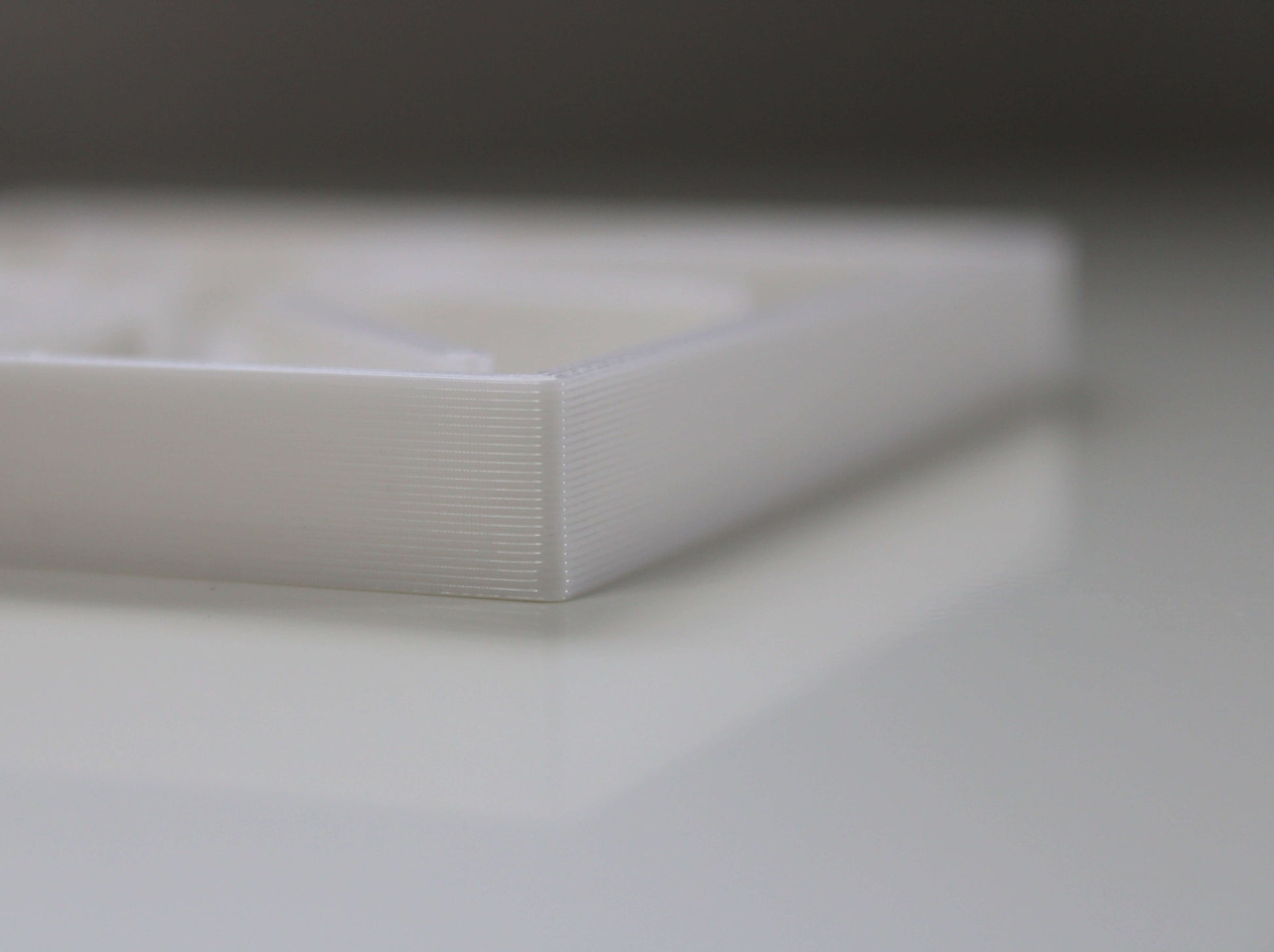 A square white 3D printed planter saucer with a raised middle