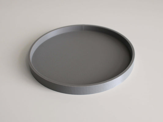 A circular gray 3D printed planter saucer with a low edge